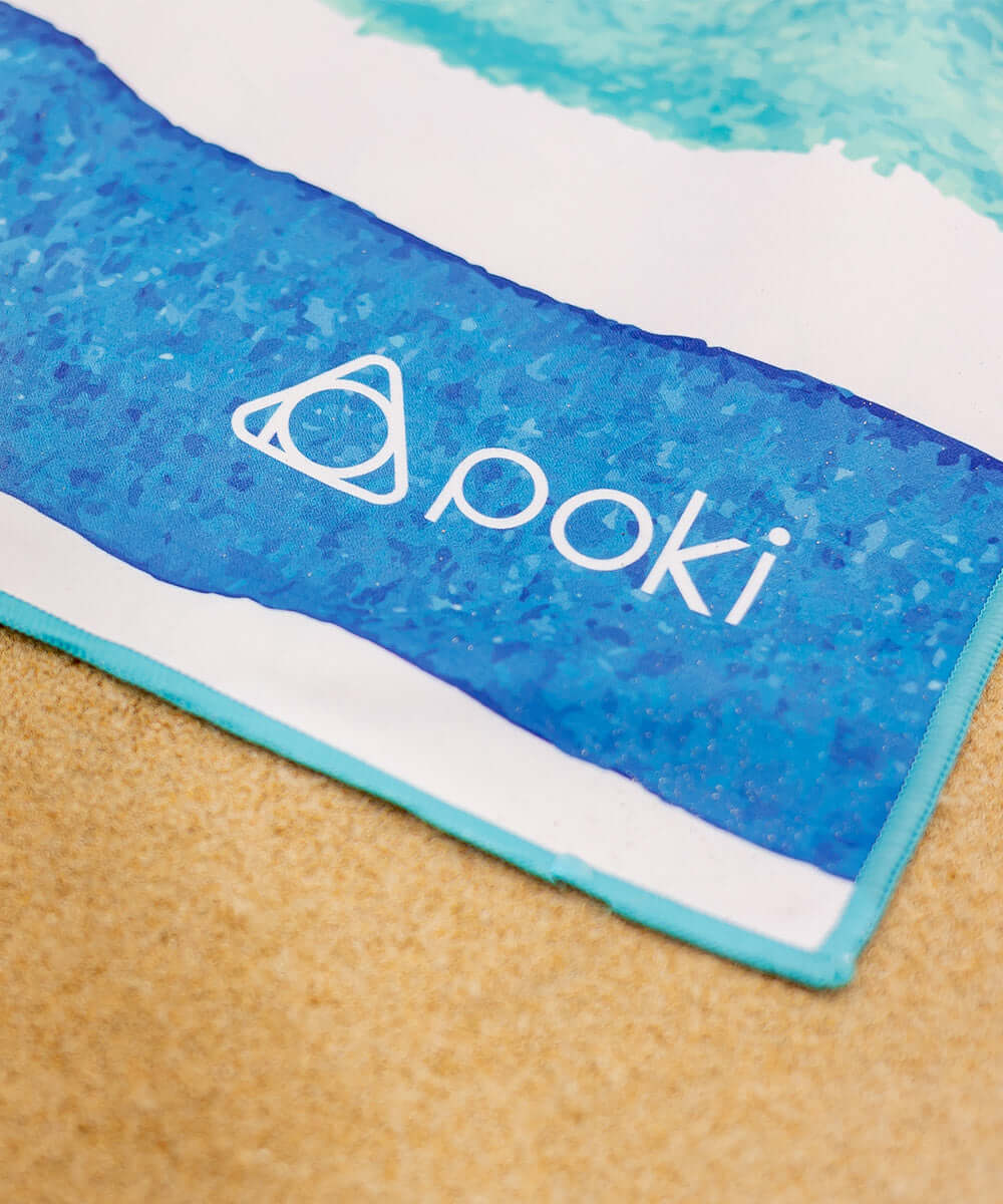 POKI快乾多用途毛巾邊緣特寫,展現色彩鮮豔的藍色圖案和品牌標誌。